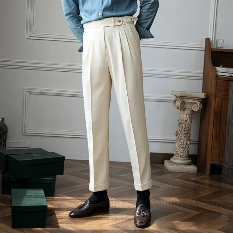 Person wearing beige pleated pants and a blue shirt in an elegant room.